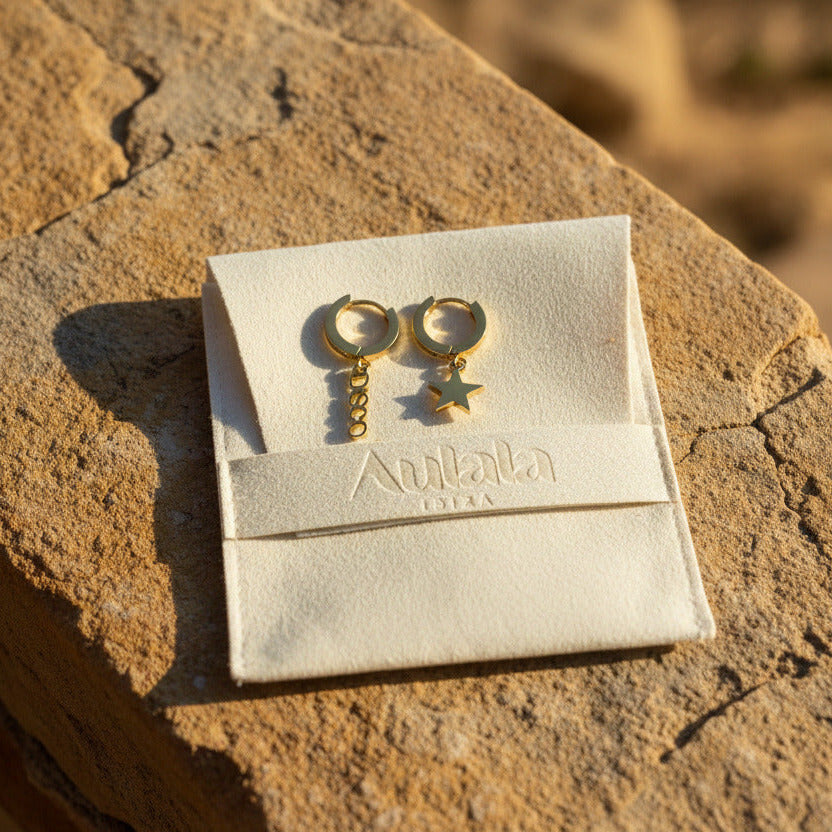 Gold hoop earrings with star and disco charms on a branded pouch