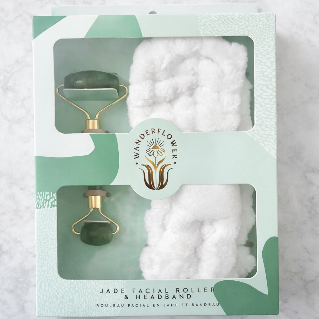 Jade facial roller and headband set with cotton pads in a 'Wanderflower' box on a marble background.