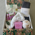Gift box with bath bombs, tea, and other items on a neutral background